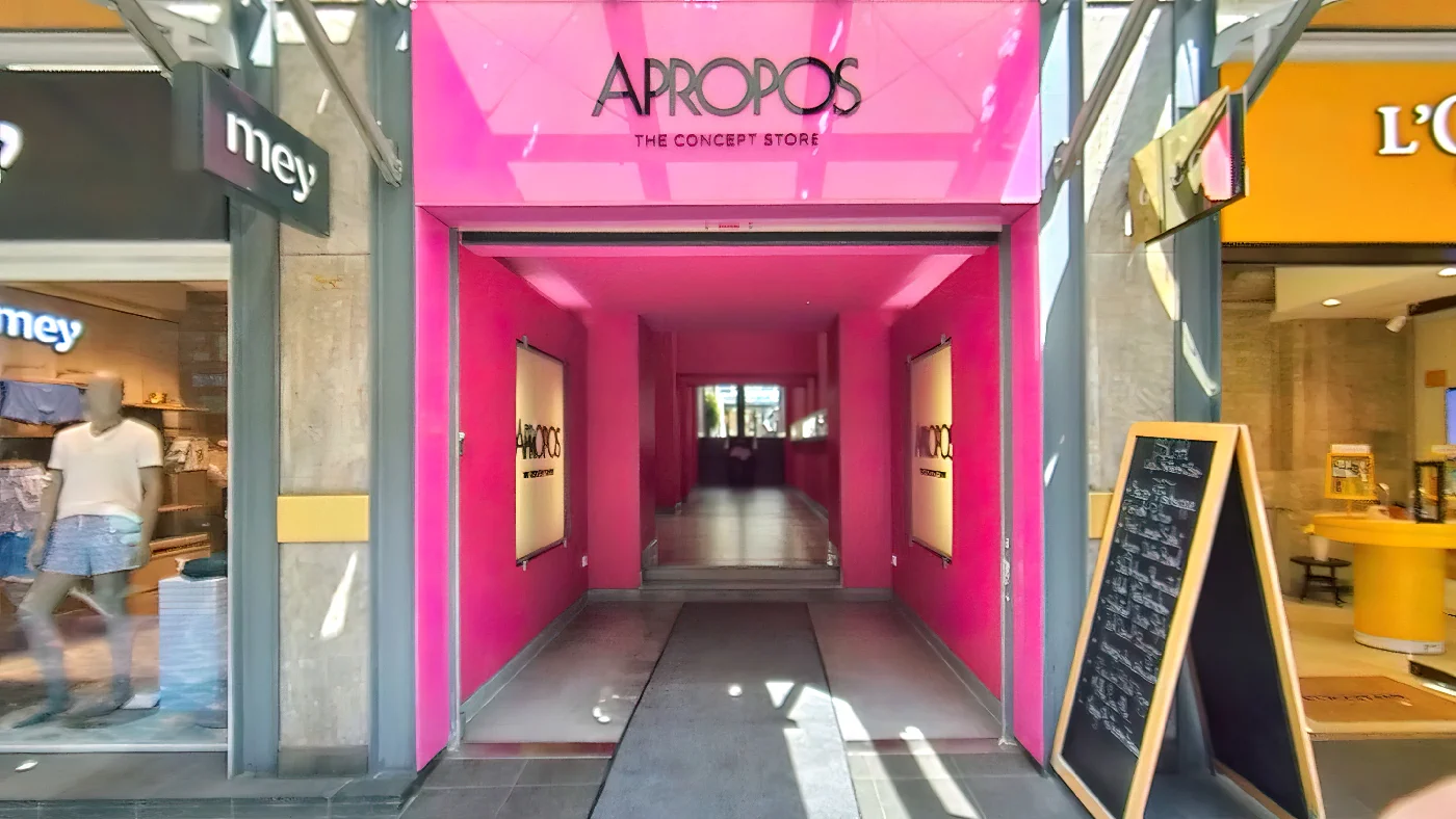APROPOS The Concept Store in Köln pink-schwarzer Tunnel-Eingang mit Kreidetafel weißer Name auf schwarzem Schild über Eingang flankiert von rosa Wänden. Conceptstore Köln Apostel-Viertel