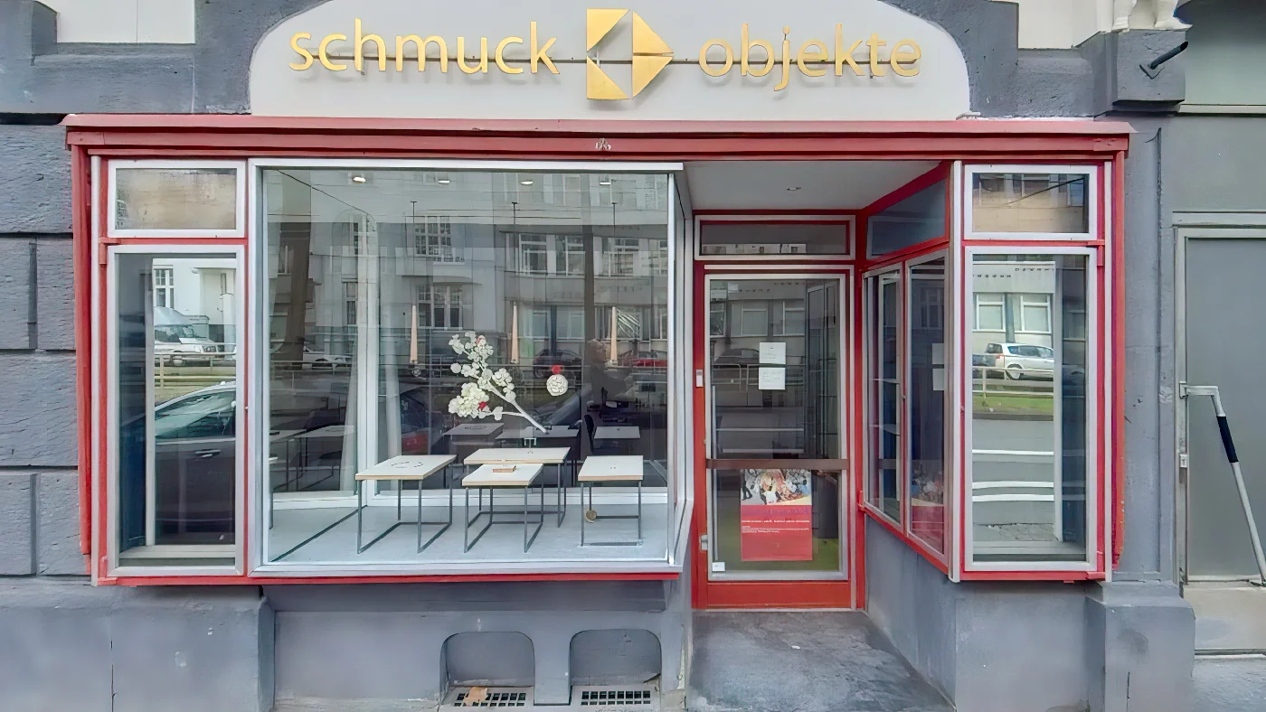 Schmuck- und Objektgeschäft Bettina Schön graue Fassade rote Akzente Name über Fenster. Modeaccessoires Köln Südstadt