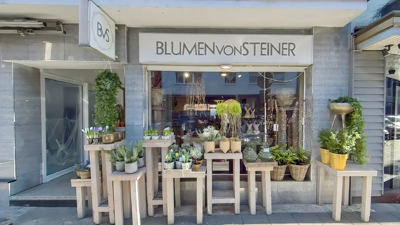 Blumen von Steiner in Köln mit weißem modernem Schild grauer Fassade Fenstern Pflanzen und Blumen davor Blumen Köln Belgisches Viertel