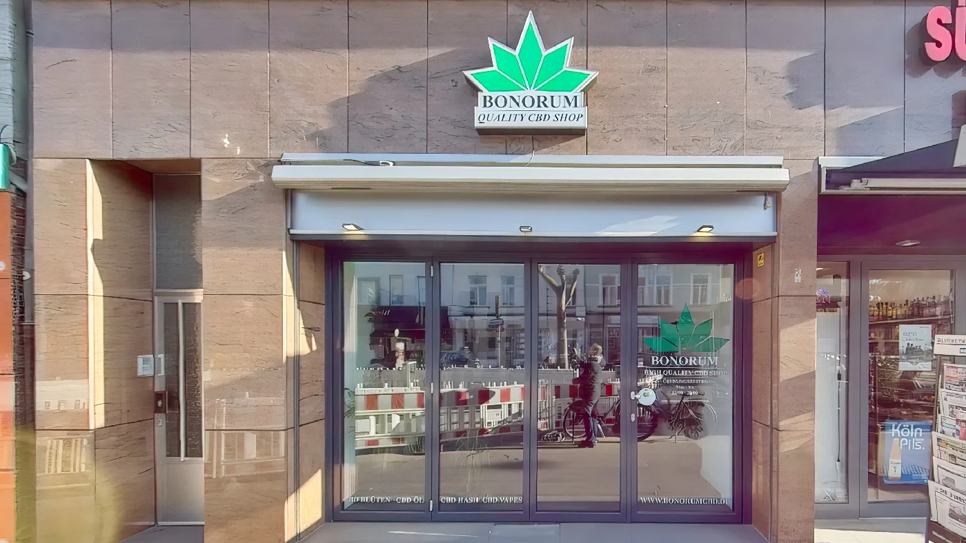 Bonorum Quality CBD Shop auf Sülzburgstraße mit grünem Logo Fenstern Markise neben Sisley Laden Cannabis Köln Sülz