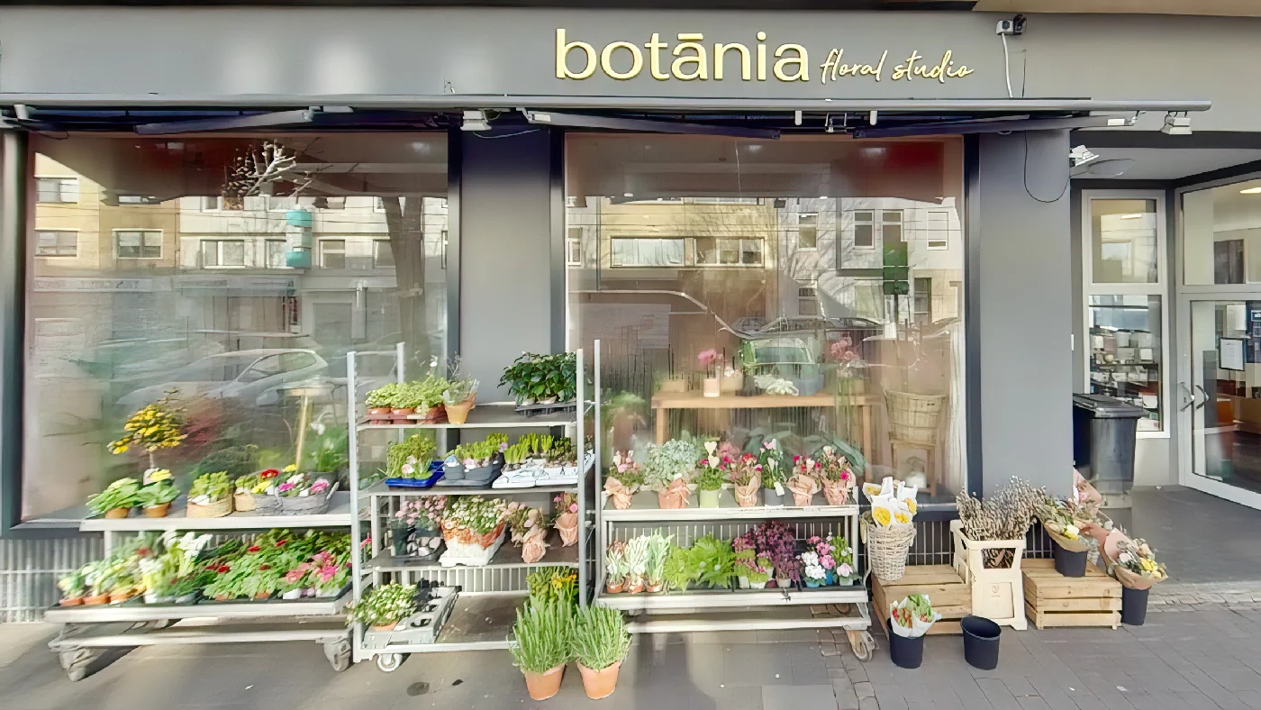 botania floral studio mit grauer Markise großen Blumenfenstern Metallregalen und Holzkisten mit Pflanzen davor Blumen Köln Sülz