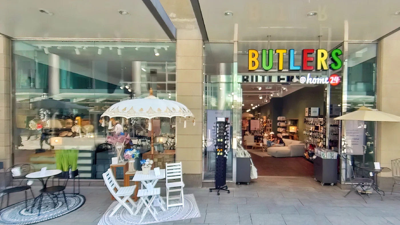 Butlers Geschäft mit Terrasse großem Schaufenster mit grünem Vordach buntem Namen Tische Stühle Pflanzen Einrichtung Köln Neumarkt-/Cäcilien-Viertel