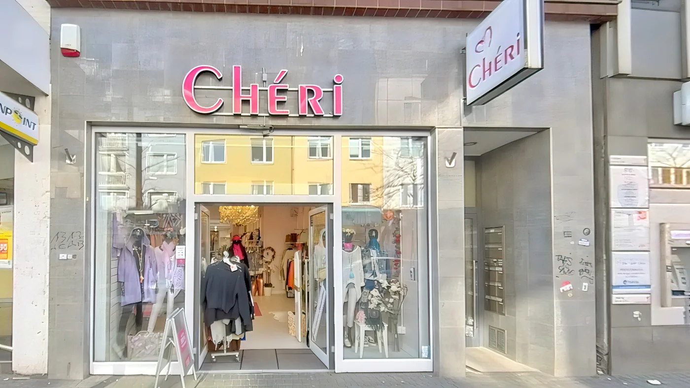 Chéri Bekleidungsgeschäft an Straßenecke graue Betonfassade pinkes Neonschild Glastüreingang Kleidung im Fenster Bekleidungsgeschäft Köln Ehrenfeld