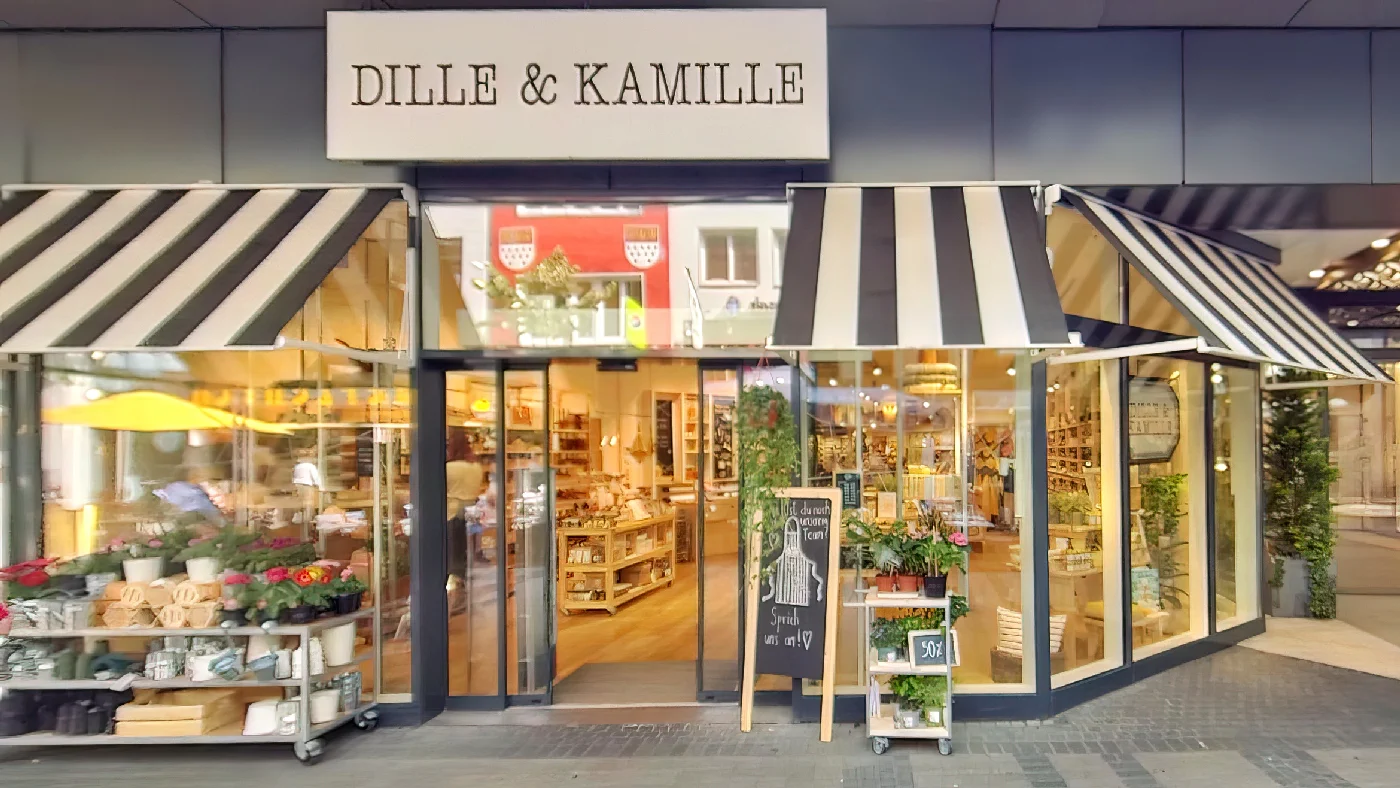 Geschäft Dille & Kamille mit weißer Beschriftung über Eingang zwei Markisen Glasfront mit Pflanzen und Haushaltswaren Tafel mit 50% Sale auf Gehweg Haushaltswaren Köln Neumarkt-/Cäcilien-Viertel