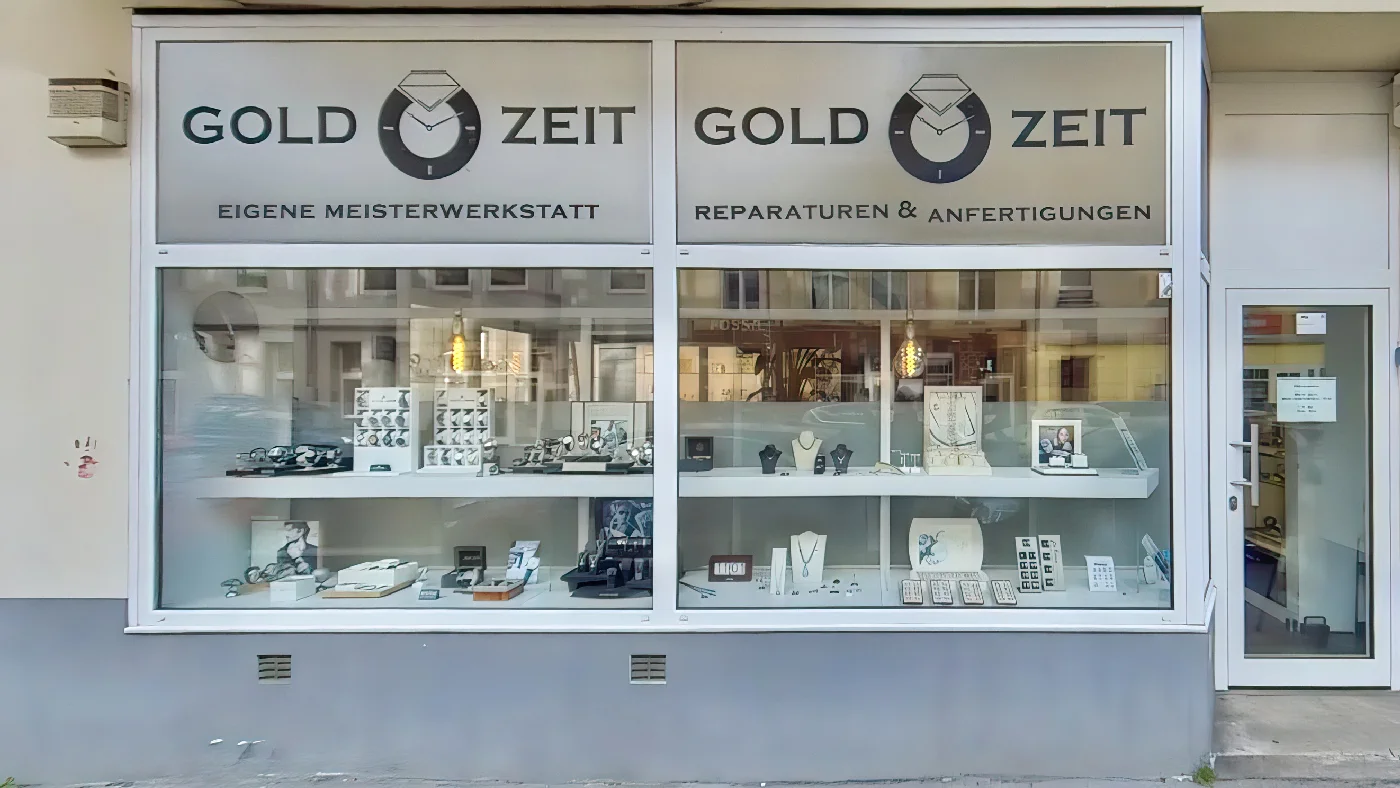 Juweliergeschäft GOLD ZEIT drei große Schaufenster gefüllt Schmuckstücken Halsketten Ohrringen Ringen graue Fassade Glastür rechten Seite Goldschmied Köln Sülz