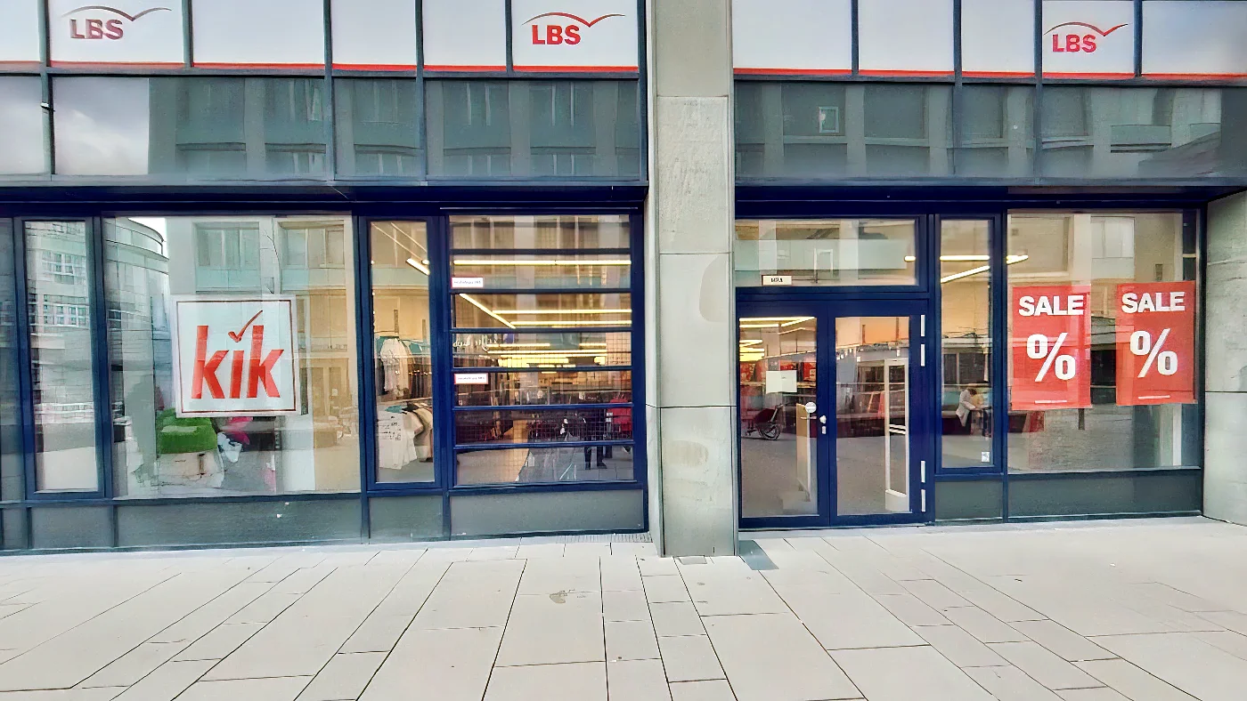 KiK Filiale Köln Ehrenfeld Schaufenster mit Sale-Schildern in grauem Gebäude an Fliesenbürgersteig. Bekleidungsgeschäft Köln Ehrenfeld