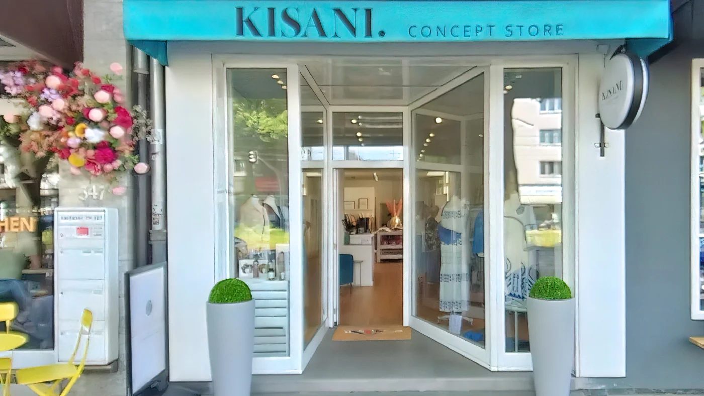 Concept Store Kisani Köln Eingang mit Blumen und blauem Vordach in Straße mit Bürgersteig. Conceptstore Köln Braunsfeld