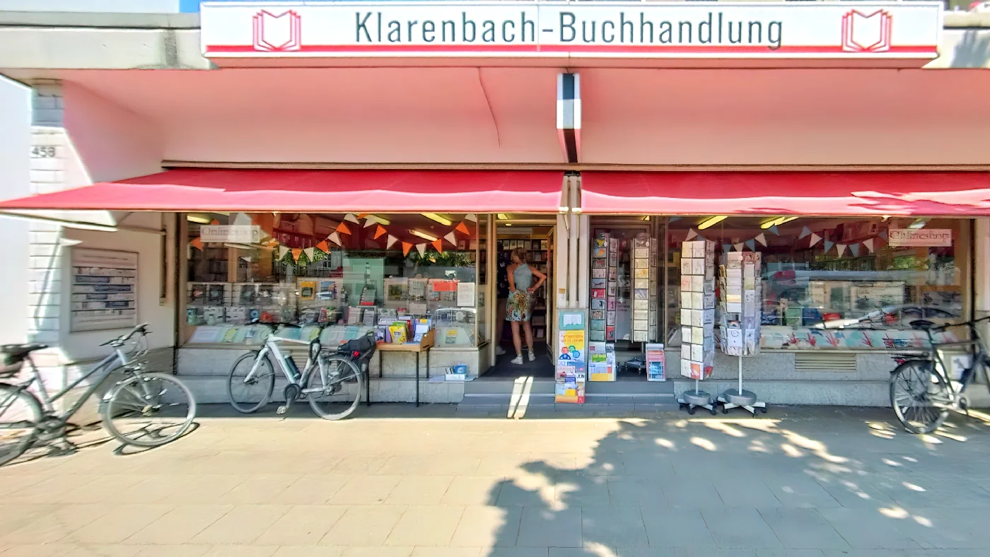Klarenbach Buchhandlung Köln-Braunsfeld mit roter Markise und Büchern im Schaufenster. Buchhandlung Köln Braunsfeld