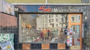 La Seda Modeschmuck: Modeschmuck im Fenster schwarzes/orangefarbenes Schild. Juweliergeschäft Köln Belgisches Viertel