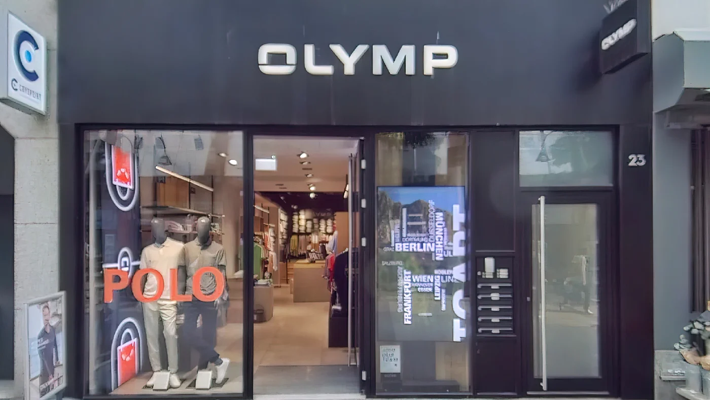 OLYMP Mannequins Kleidung Schild “POLO” Augensymbol Glasfront moderne Architektur trendige Outfits exklusive Modemarken Herrenmodengeschäft Köln Neumarkt-/Cäcilien-Viertel