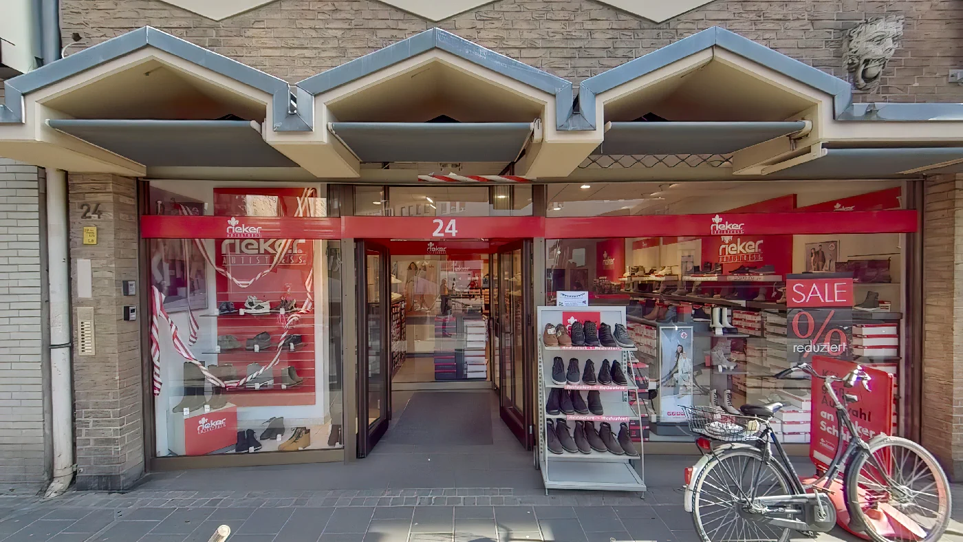 Rieker-Store Chlodwigplatz Schuhgeschäft mit roter-weißer Beschilderung und Fahrrad davor Schuhe Köln Severins-Viertel
