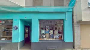 Schauplatz: türkisfarbene Fassade Kleidung und Accessoires im Fenster. Damenmodengeschäft Köln Rathenau-/Komponistenviertel