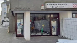 Weiss Rad + Service Manfred Weiss graue Fassade Fahrräder und Zubehör im Fenster "SEVERINSKIRCHPLATZ"-Schild sichtbar. Fahrrad Köln Severins-Viertel